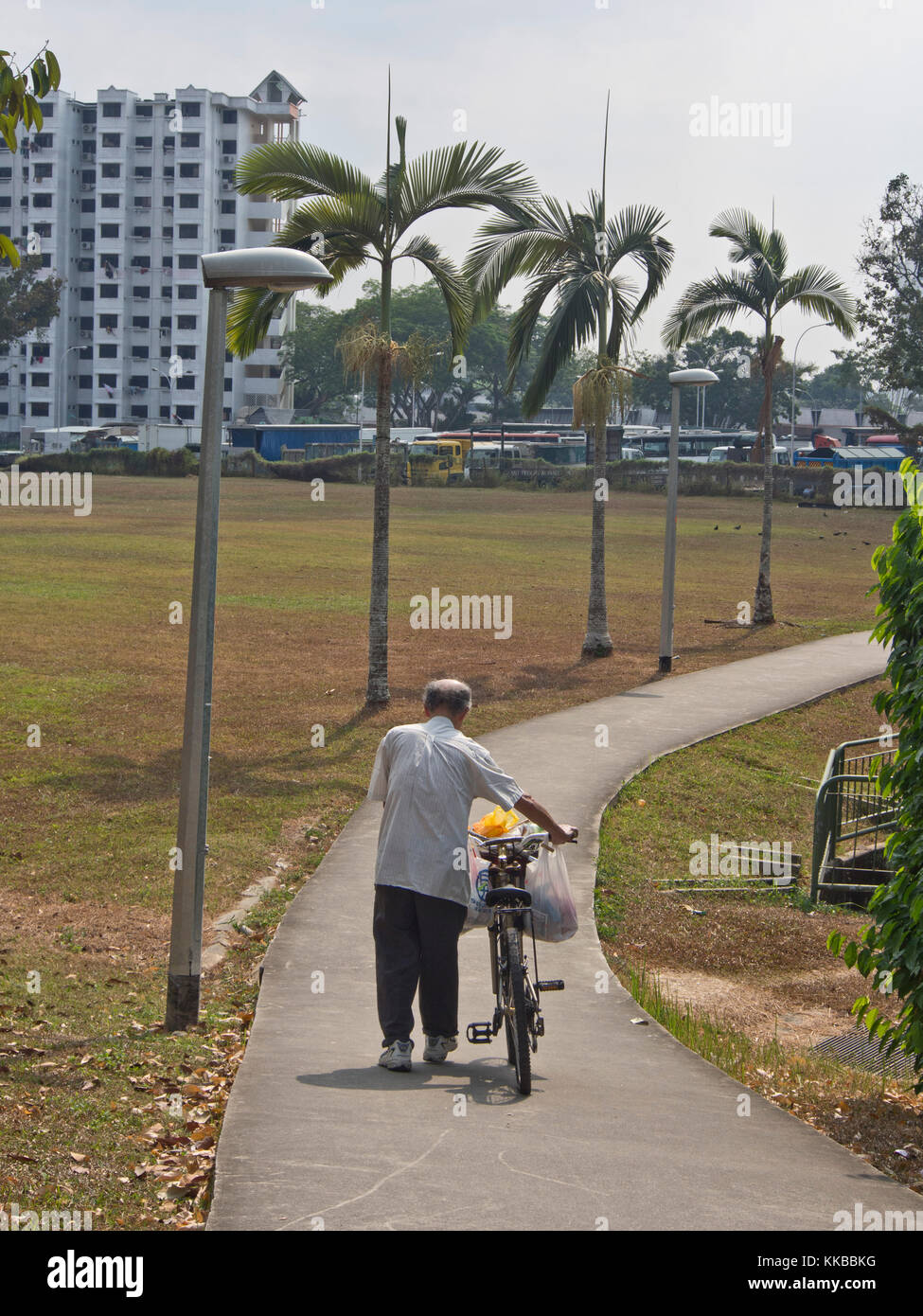 Senior citizen walking his bicycle in Singapore Stock Photo