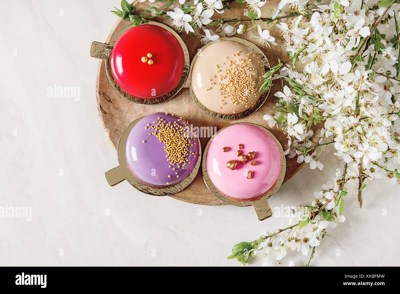 Fashionable mousse cake with a mirror glaze decorated with spring flowers. Light white background Stock Photo