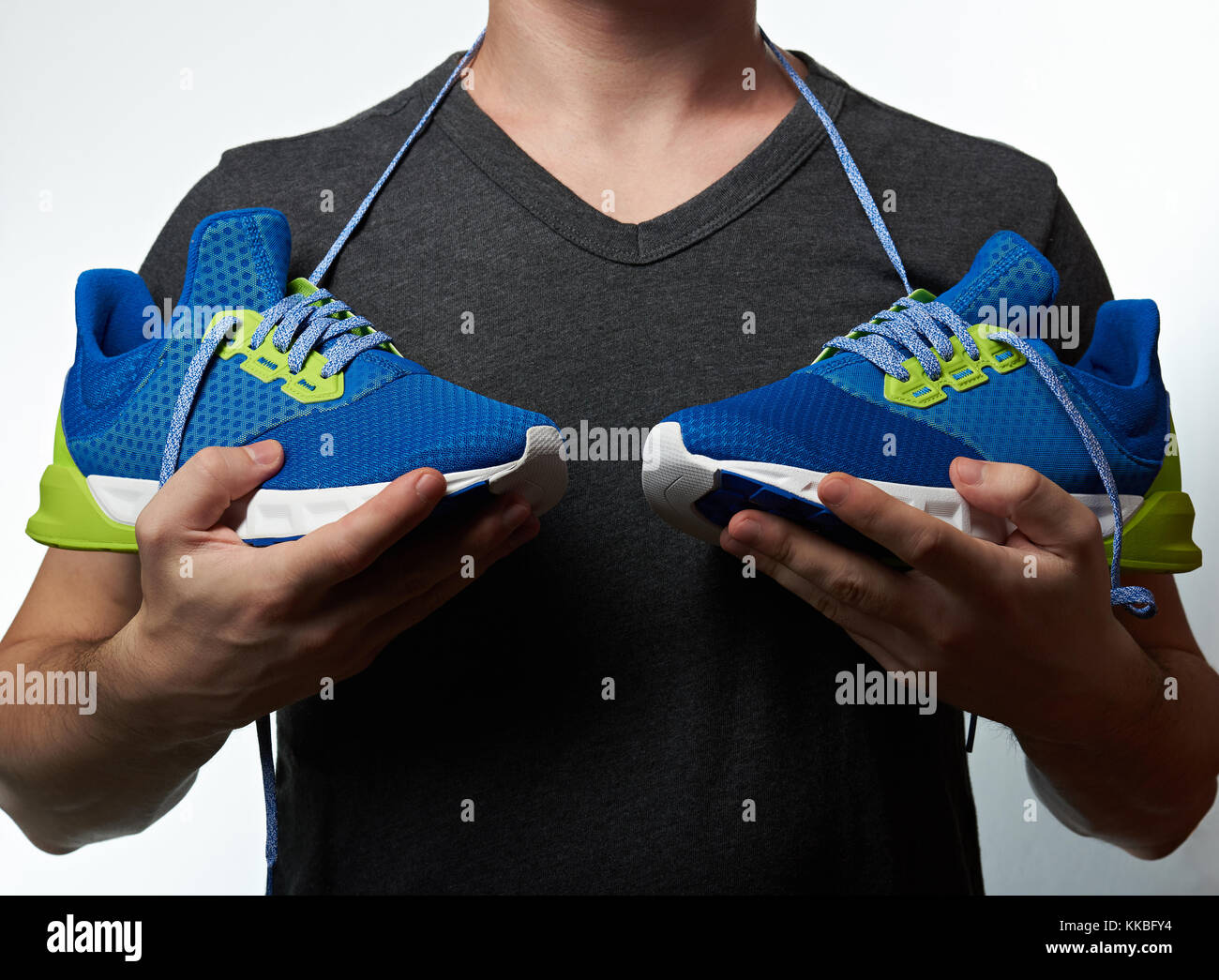 Man holding modern running shoes concept isolated on white background. Man with sporty colorful shoes Stock Photo