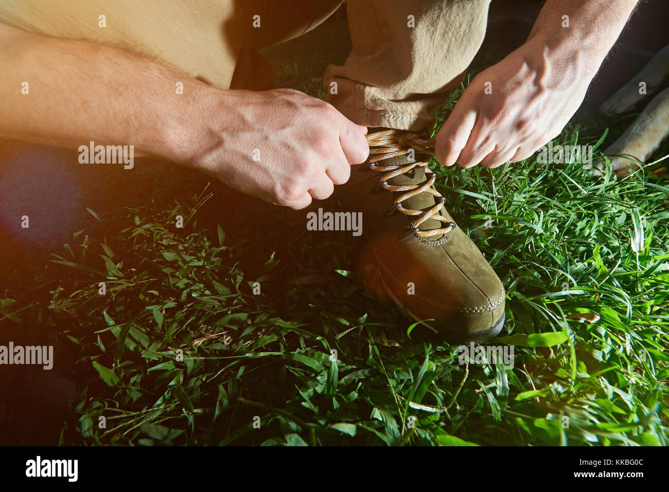 tying hiking shoes lace closeup on green grass background. Tourist tie