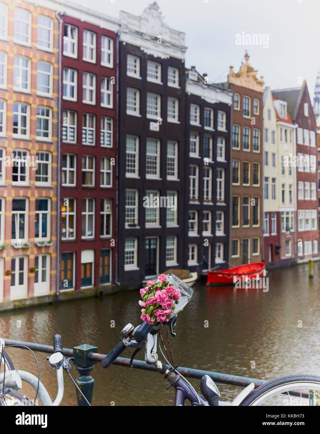 Bunch of pink flowers attached to handlebars of a bike by canal, Amsterdam, Netherlands Stock Photo