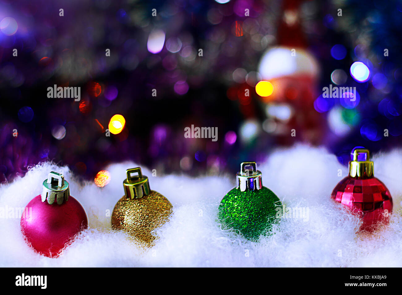 Colored christmas decorative  balls in the snowdrift on blurred defocused festive background with sparkling lights. Christmas or new year greeting car Stock Photo
