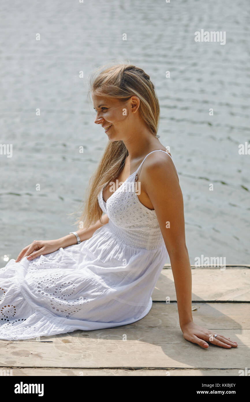 Girl sitting on pier and looking at the river Stock Photo - Alamy