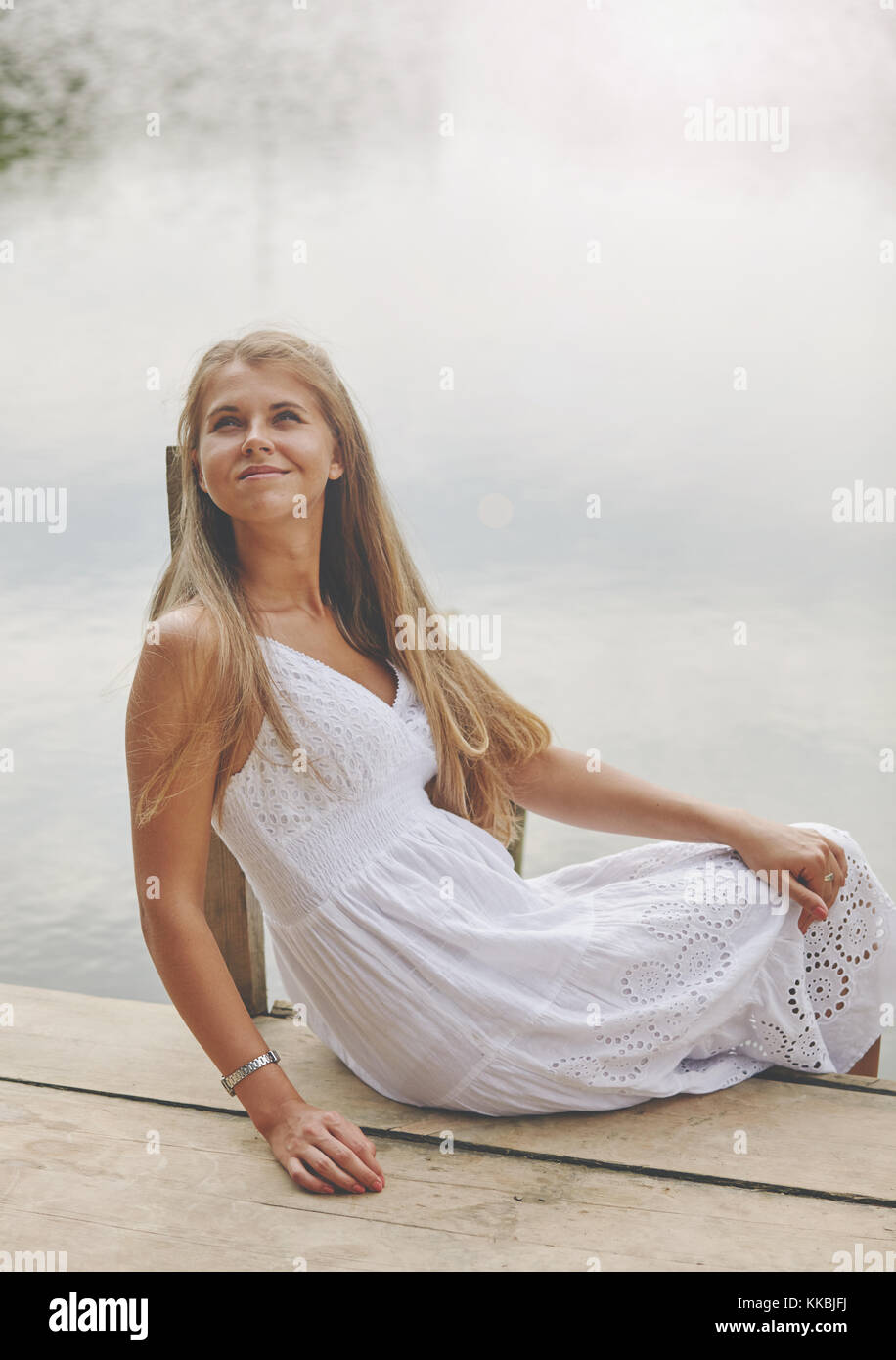 Girl sitting on pier and looking at the river Stock Photo - Alamy