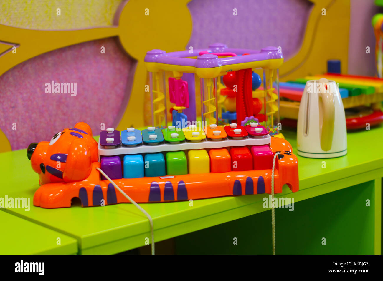 Rainbow colored xylophone on the table among toys in baby room. Stock Photo