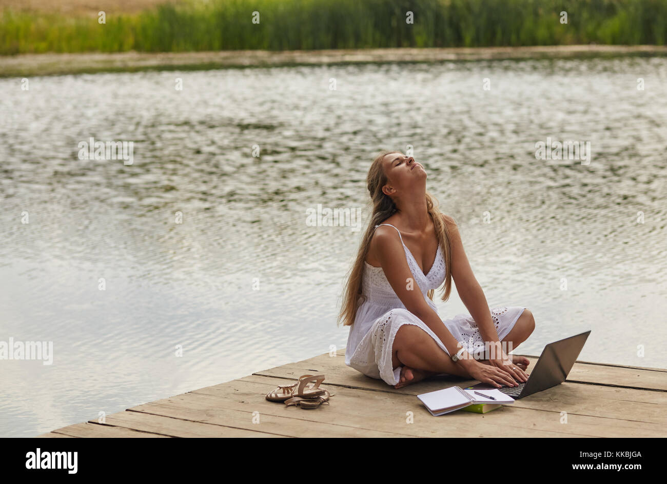 Girl sitting on pier and looking at the river Stock Photo - Alamy