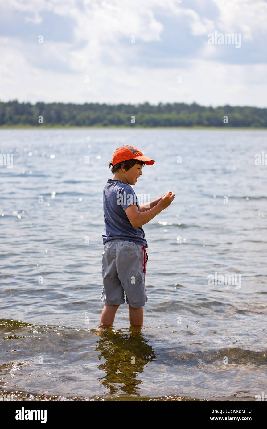 A boy throwing stones into a lake, polish Lake District Mazury, holidays, leisure during