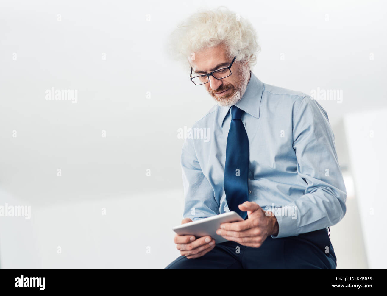 Confident mature businessman working and using a digital tablet Stock ...