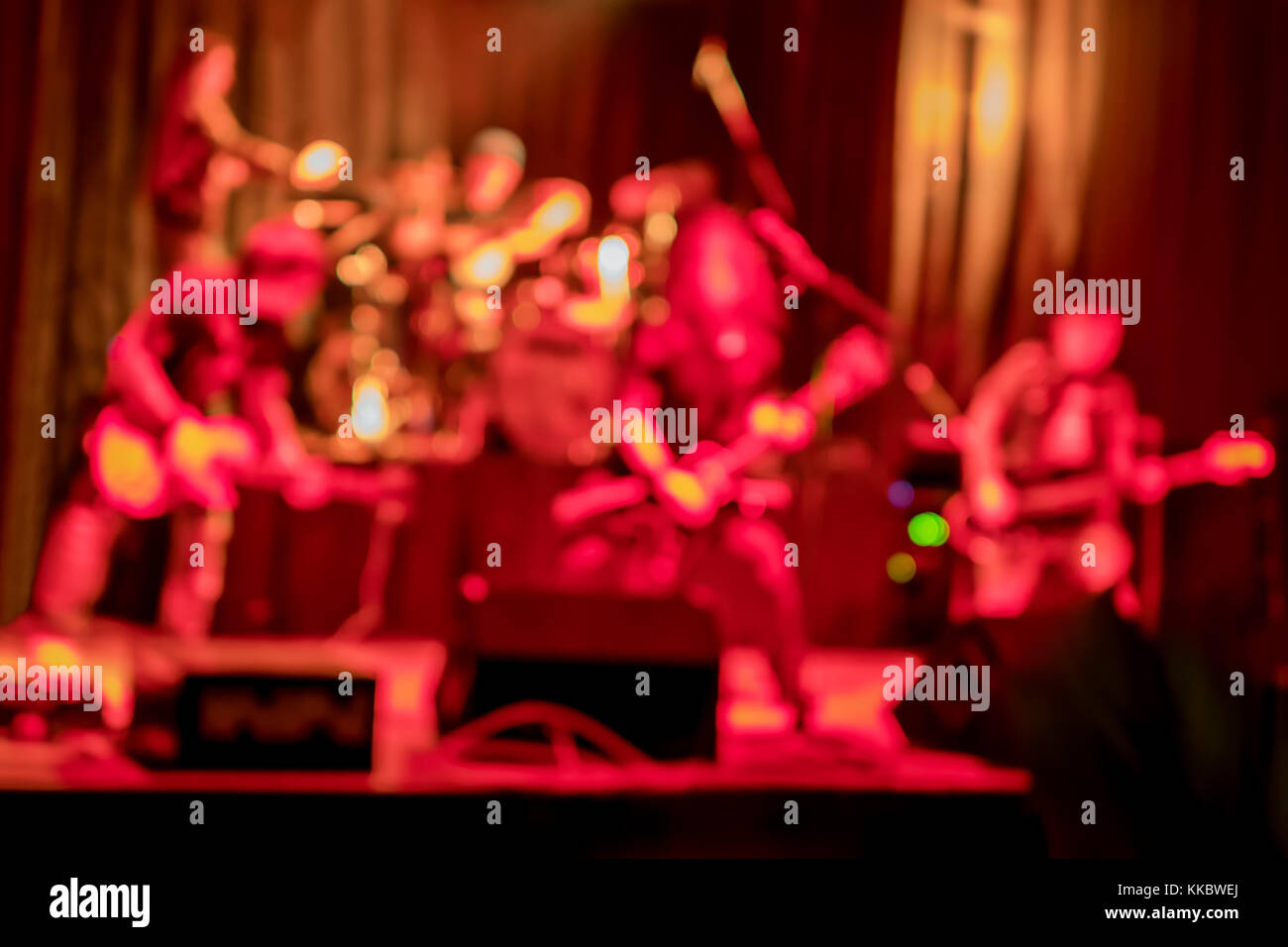 Performance of a rock band with guitarists and a drummer on stage, blurry, in red tones Stock Photo