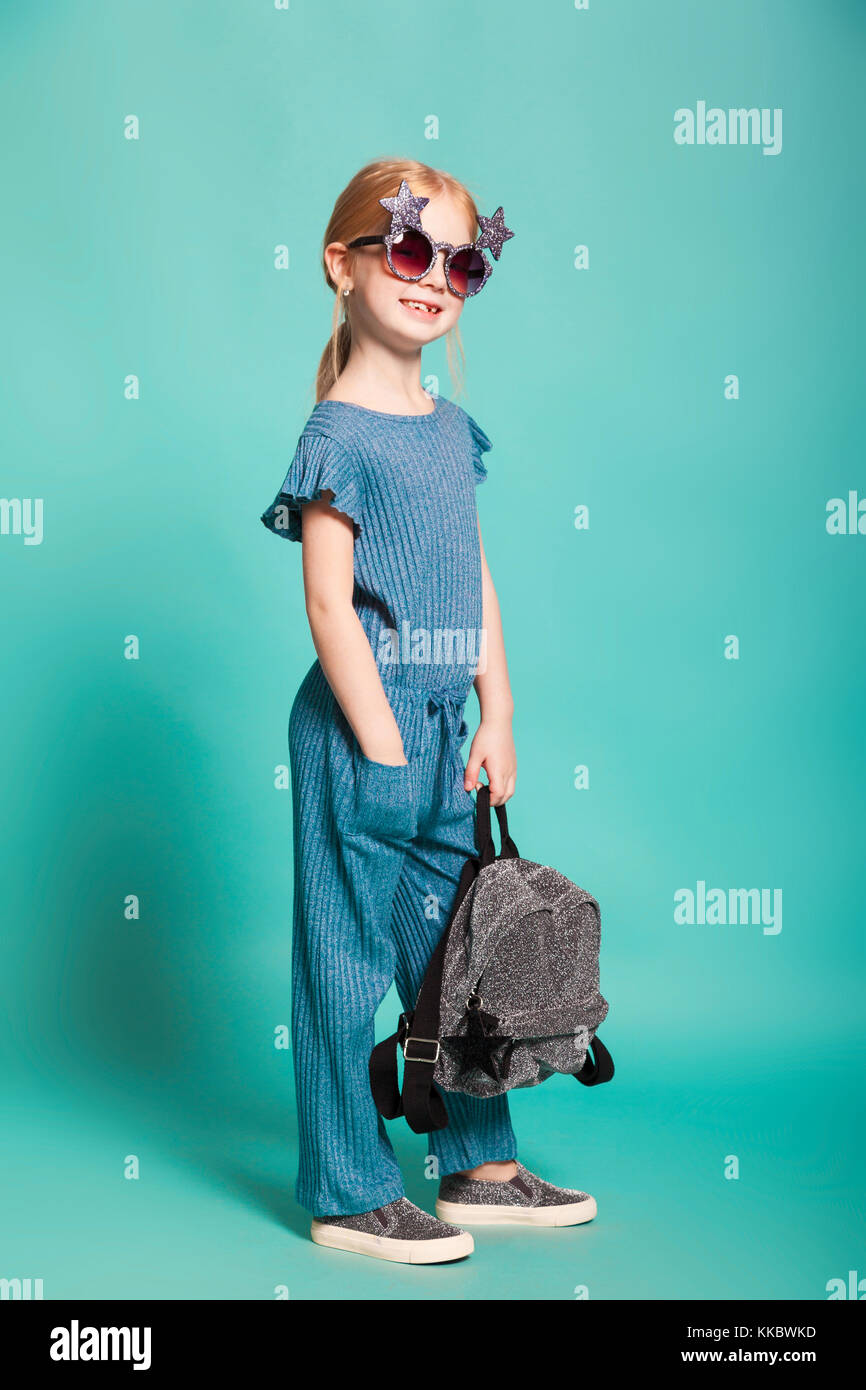 little girl with a tail in stylish clothes and sunglasses on blue
