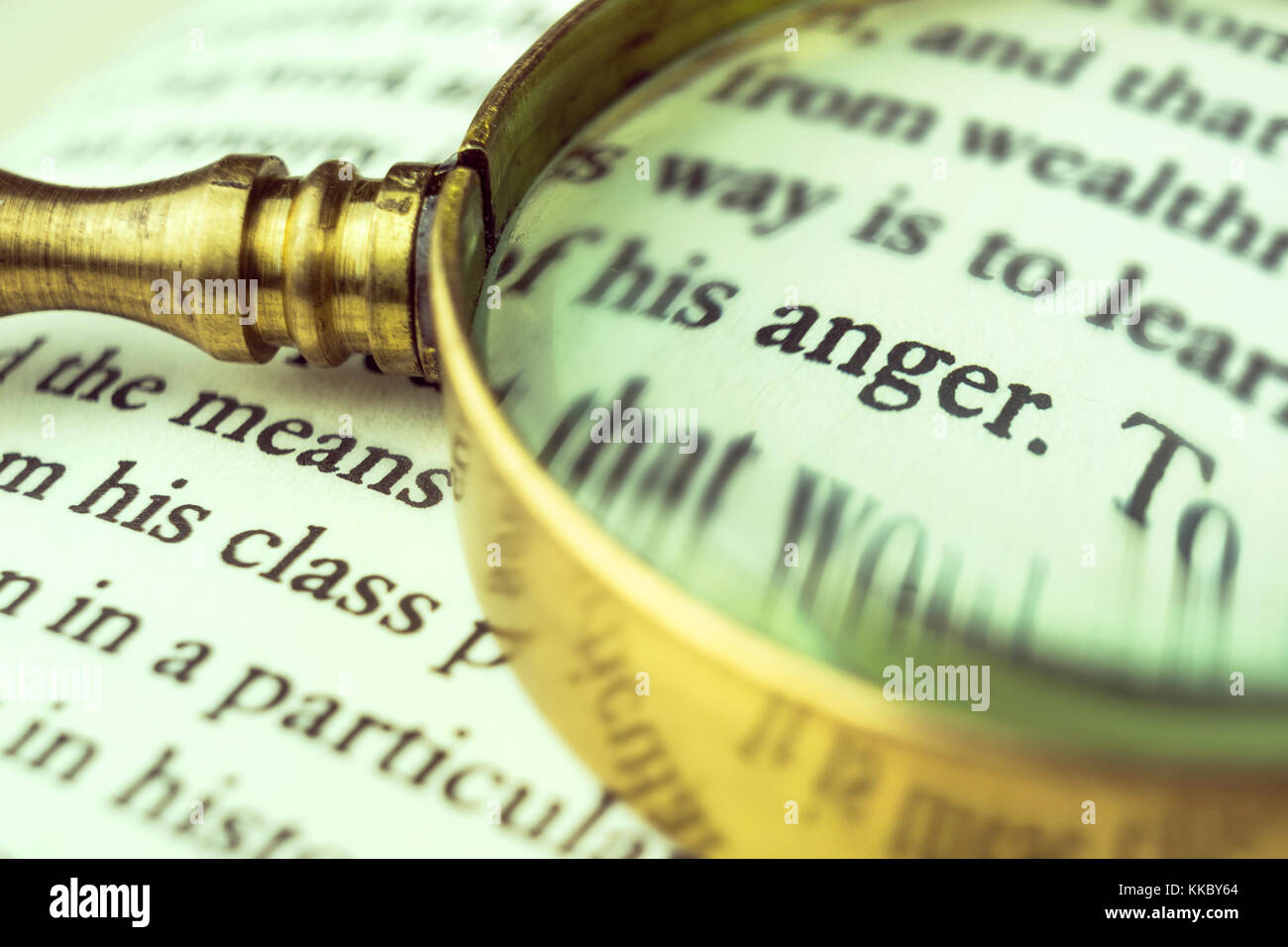 The word 'anger' emphasized by a magnifying glass and wrapped with blurry text. Stock Photo
