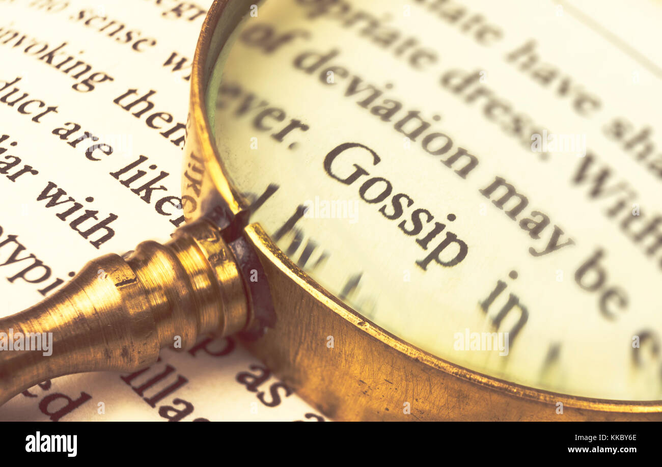 The word 'gossip' emphasized by a magnifying glass and wrapped with blurry text. Stock Photo