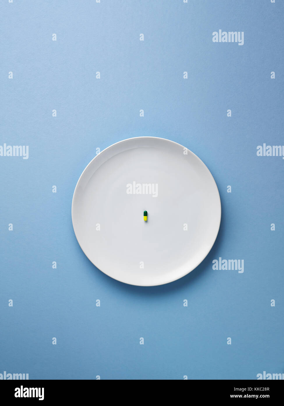 single pill in  the centre of a plate, shot from above on a powder blue background Stock Photo
