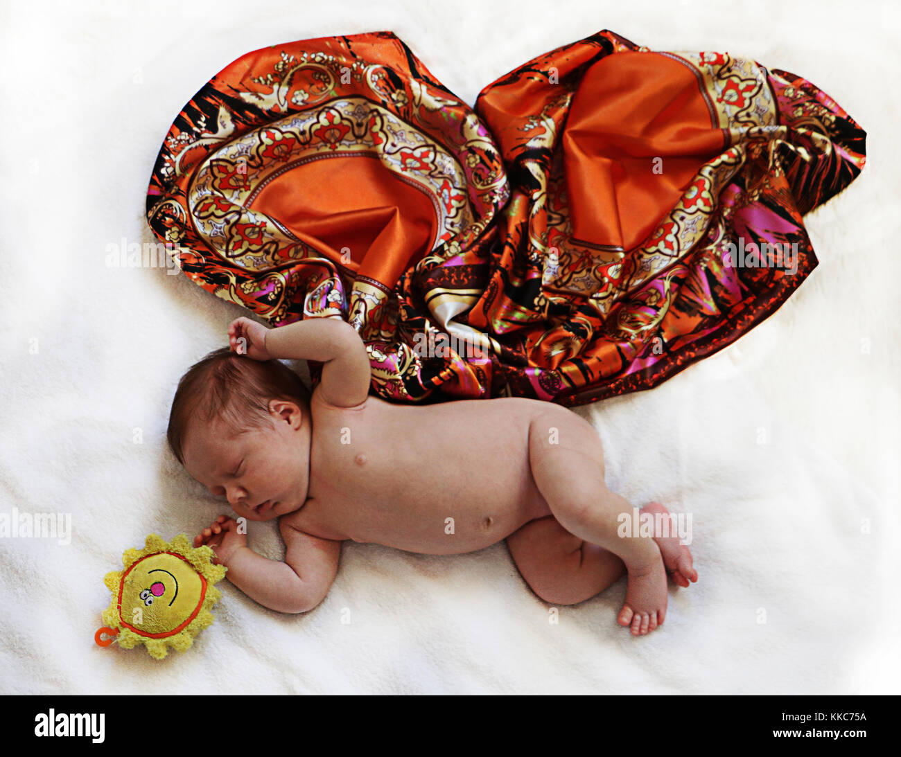 Cute newborn few days old baby with colored butterfly wings made of fabric sleeping on white blanket. Stock Photo