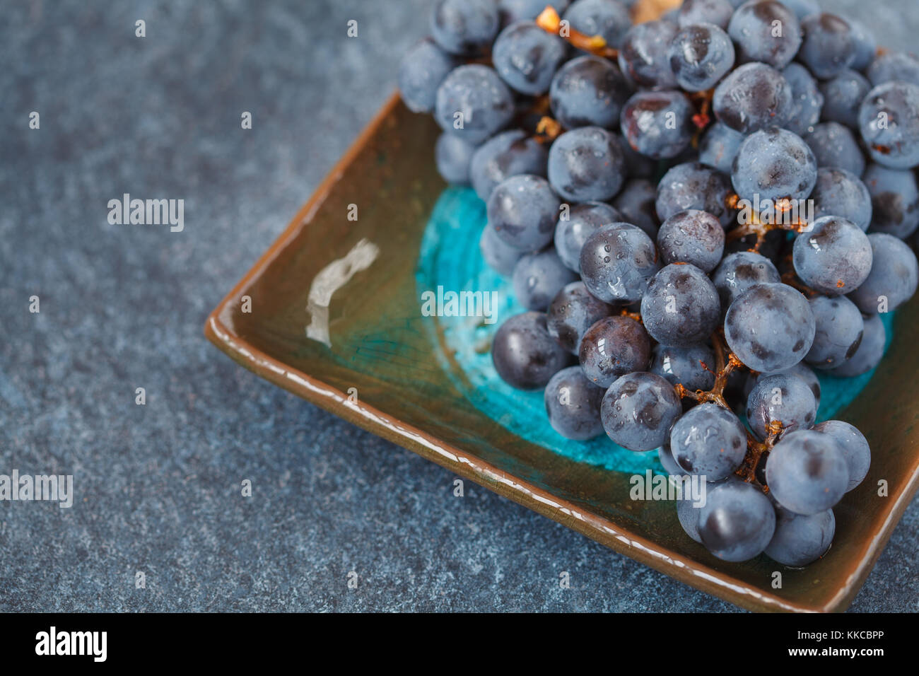 Red wine grape on a dark plate. Blue grapes, dark grapes Stock Photo