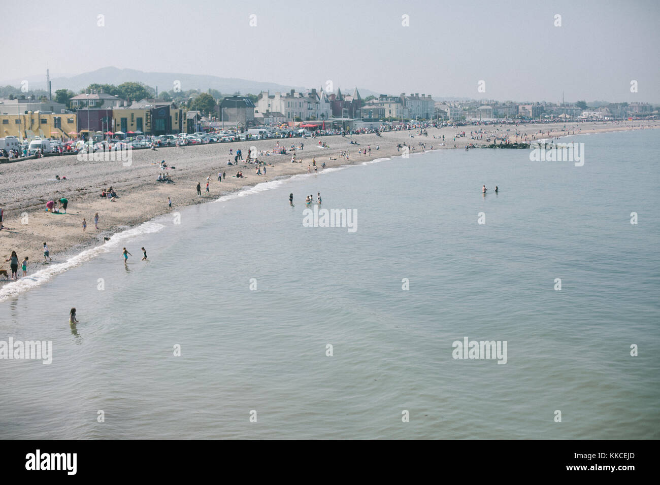 People on the stony beach in Bray enjoying sunny May day realxing , walking and having fun in the water. Stock Photo