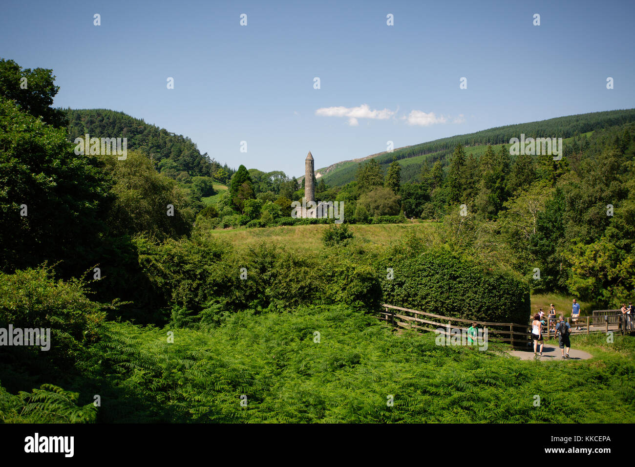 Tourists visiting beautiful Glendalough Lower Valley with view on a Monastic site with round tower. Wicklow Mountain National Park, Ireland Stock Photo