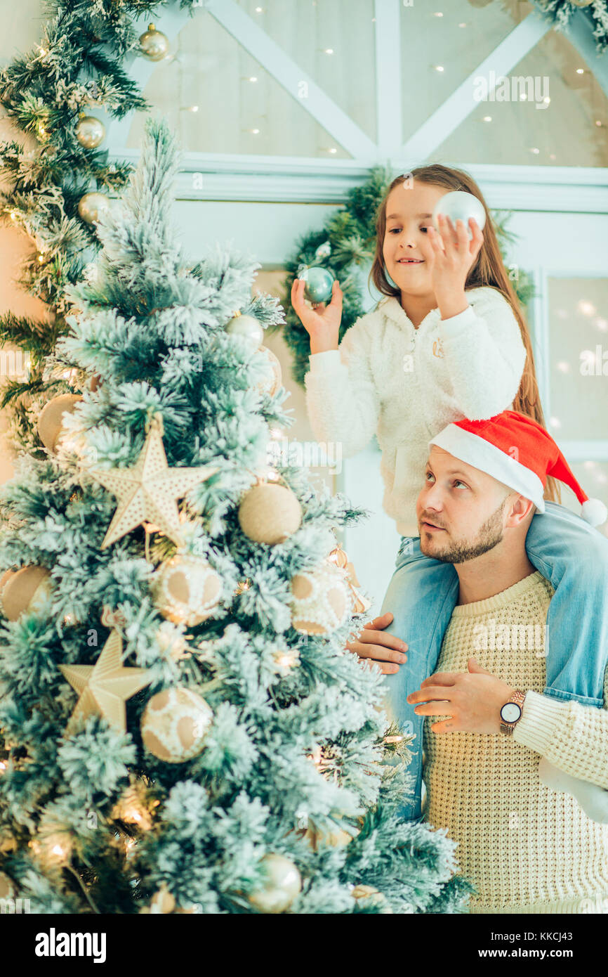 girl helping father decorating Christmas tree, holding some Christmas ...