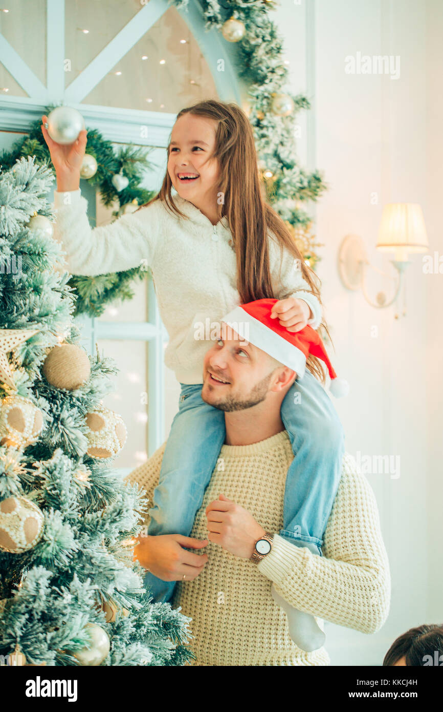 girl helping father decorating Christmas tree, holding some Christmas ...
