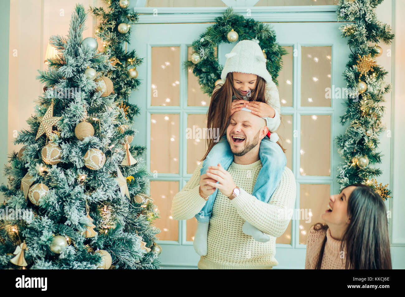 girl helping father decorating Christmas tree, holding some Christmas ...