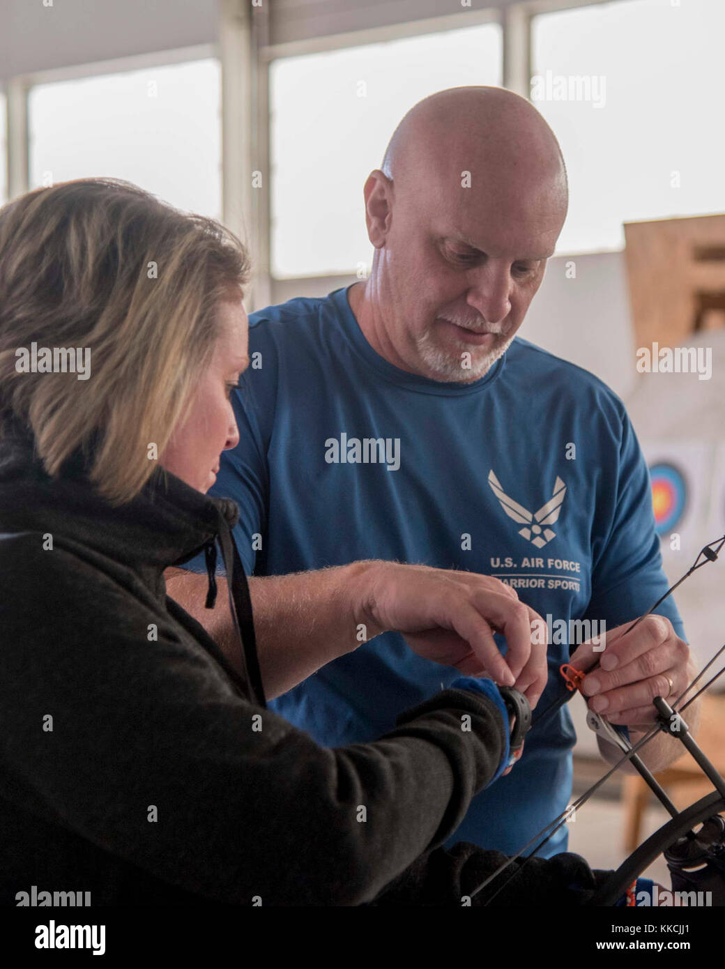 Jeff Matuszak, right, Warrior CARE coach, teaches, Amara Klika, Warrior CARE participant, how to position her hand on a compound bow during an archery training session at Joint Base Andrews, Md., Nov 13, 2017. This was one of many events hosted during the week-long Air Force Wounded Warrior CARE Event, which taught injured Airmen about the many programs available to help them rehabilitate. (U.S. Air Force photo by Airman 1st Class Valentina Lopez) Stock Photo