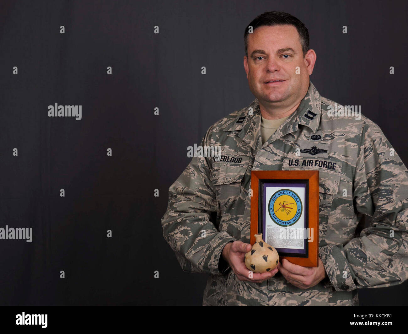 Capt. Travis Trueblood, 11th Wing assistant staff judge advocate, poses for a photo at Joint Base Andrews, Md., Nov. 16, 2017. Trueblood holds Native American art and the Choctaw Nation seal, which were gifted to him during his encounters and meetings with other members of the Choctaw Nation. November is designated as National American Indian Heritage Month, a time to celebrate the cultures, traditions, histories, and acknowledge the contributions of Native Americans.  (U.S. Air Force photo by Airman Michael Murphy) Stock Photo