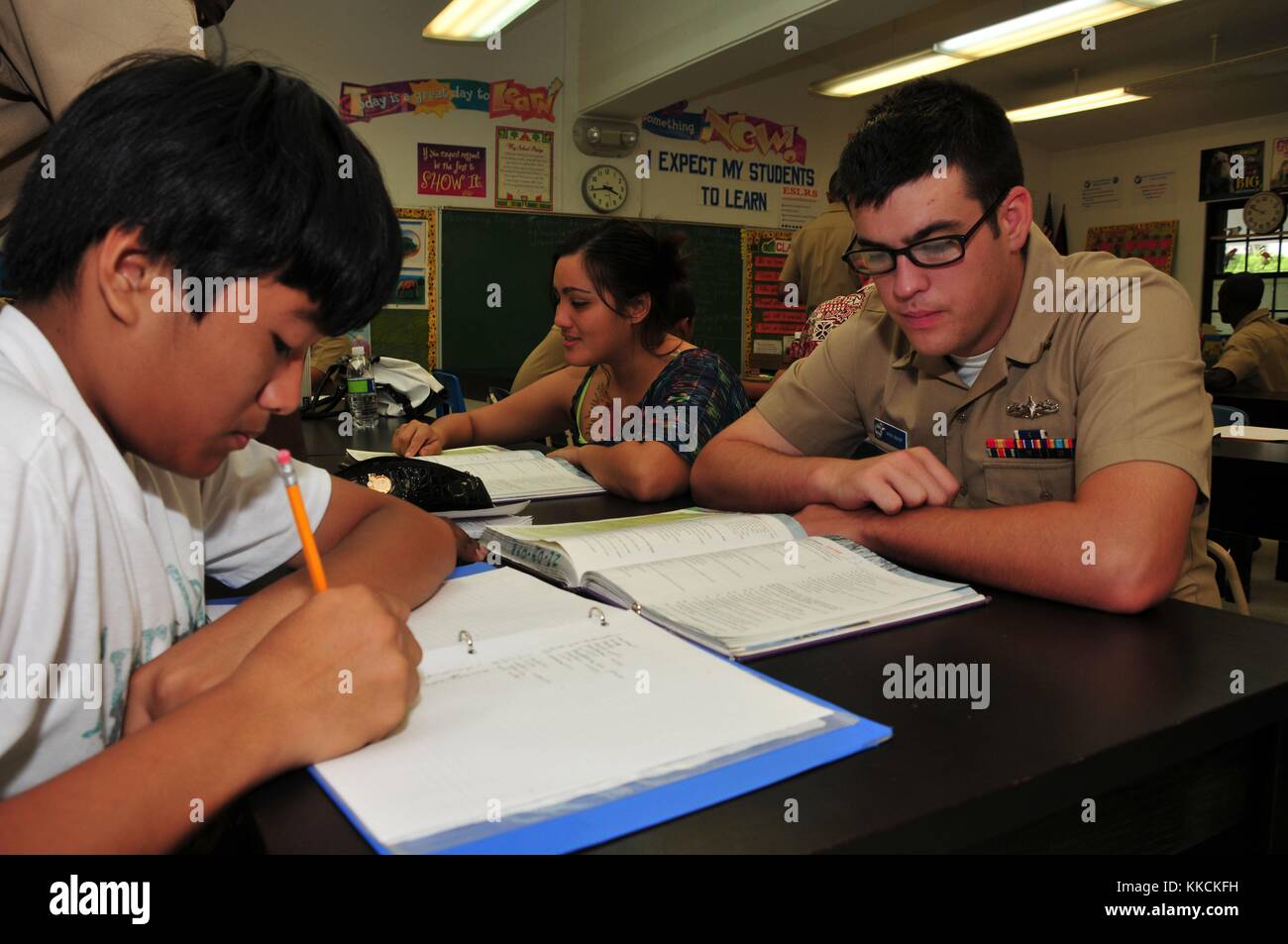 Religious Programs Specialist Seaman Donald Bishop, assigned to the submarine tender USS Emory S Land AS 39, explains math concepts and formulas to a student from Jose Rios Middle School during the Saturday Scholars tutoring program, Piti, Guam. Image courtesy Mass Communications Specialist 2nd Class Jared Aldape/US Navy, 2012. Stock Photo