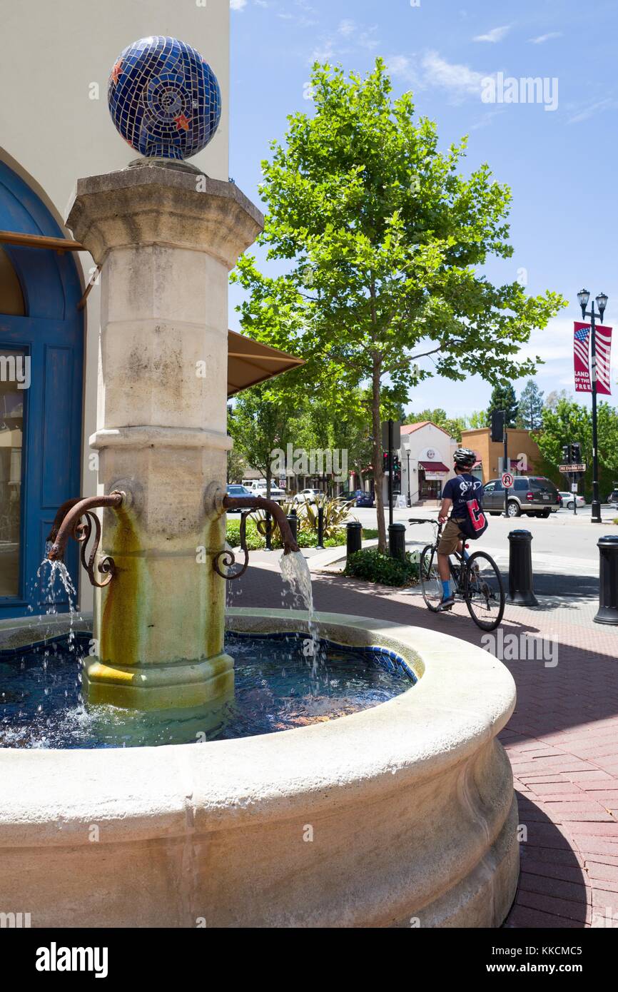 A bicyclist passes by a Mediterranean-style fountain in a square off of Mount Diablo Boulevard in Lafayette, California, one of the wealthiest communities in the San Francisco Bay Area, Lafayette, California, 2016. Stock Photo