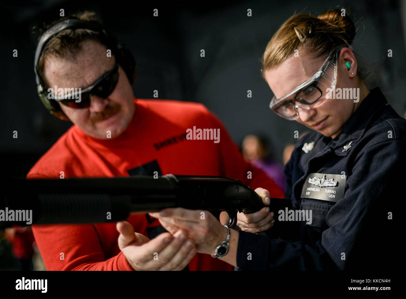 INDIAN OCEAN (Nov. 26, 2017) Aviation Ordnanceman 1st Class John Shreve instructs Logistics Specialist 2nd Class Anzhelika Turano on proper weapon handling while shooting a M500 shotgun off the fantail of the aircraft carrier USS Theodore Roosevelt (CVN 71) during a weapons qualification course. Theodore Roosevelt is deployed in support of maritime security operations and theater security cooperation efforts. (U.S. Navy photo by Mass Communication Specialist 3rd Class Robyn B. Melvin) Stock Photo