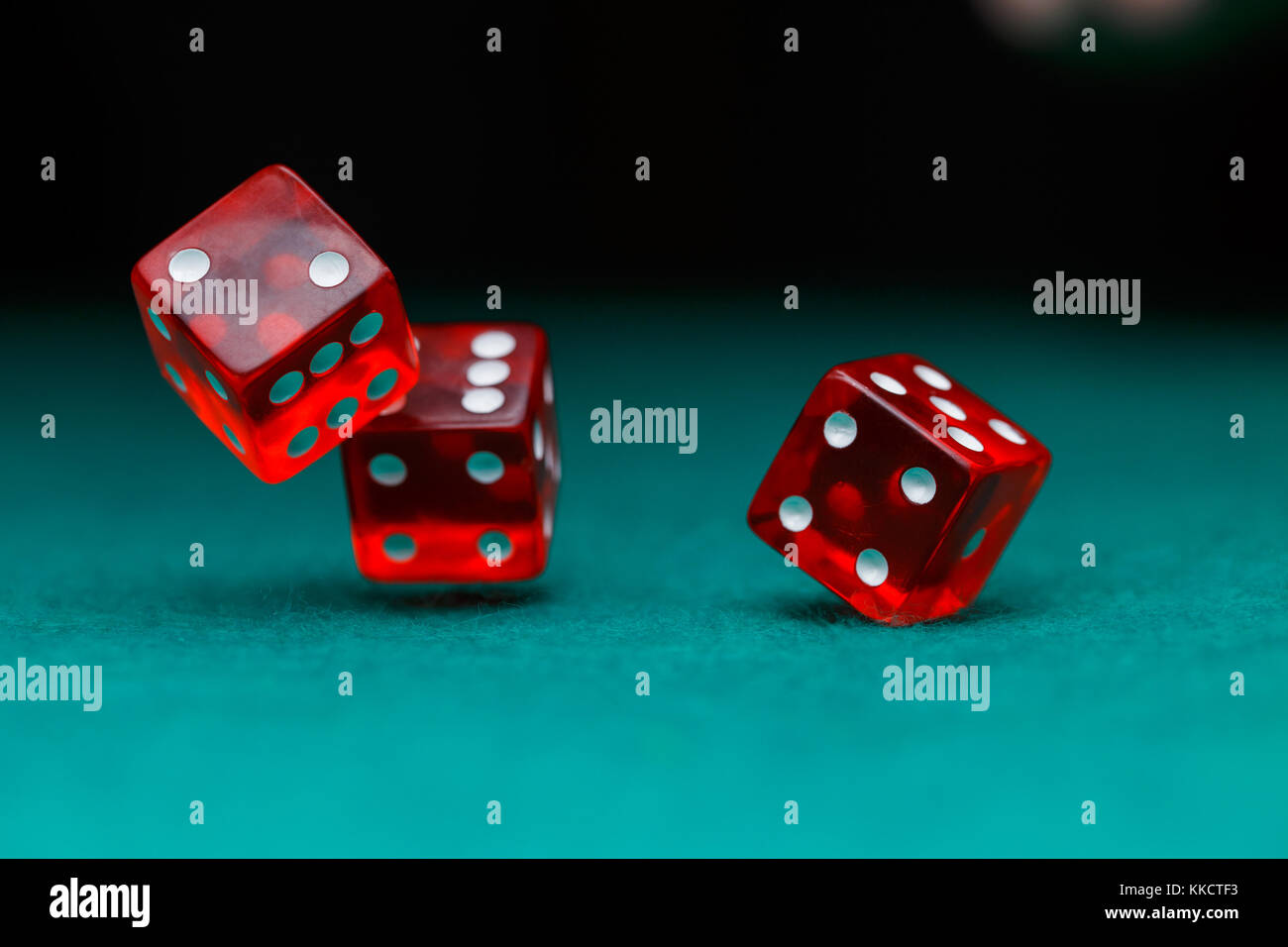 Image of several red dice falling on green table on black background Stock Photo