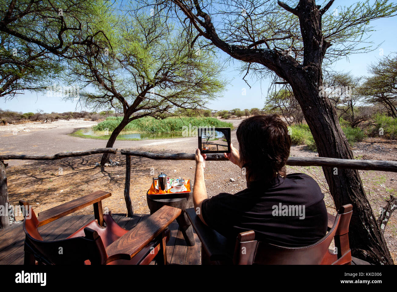 Man taking picture with tablet at Onguma Tree Top Camp, Onguma Game Reserve, Namibia, Africa Stock Photo