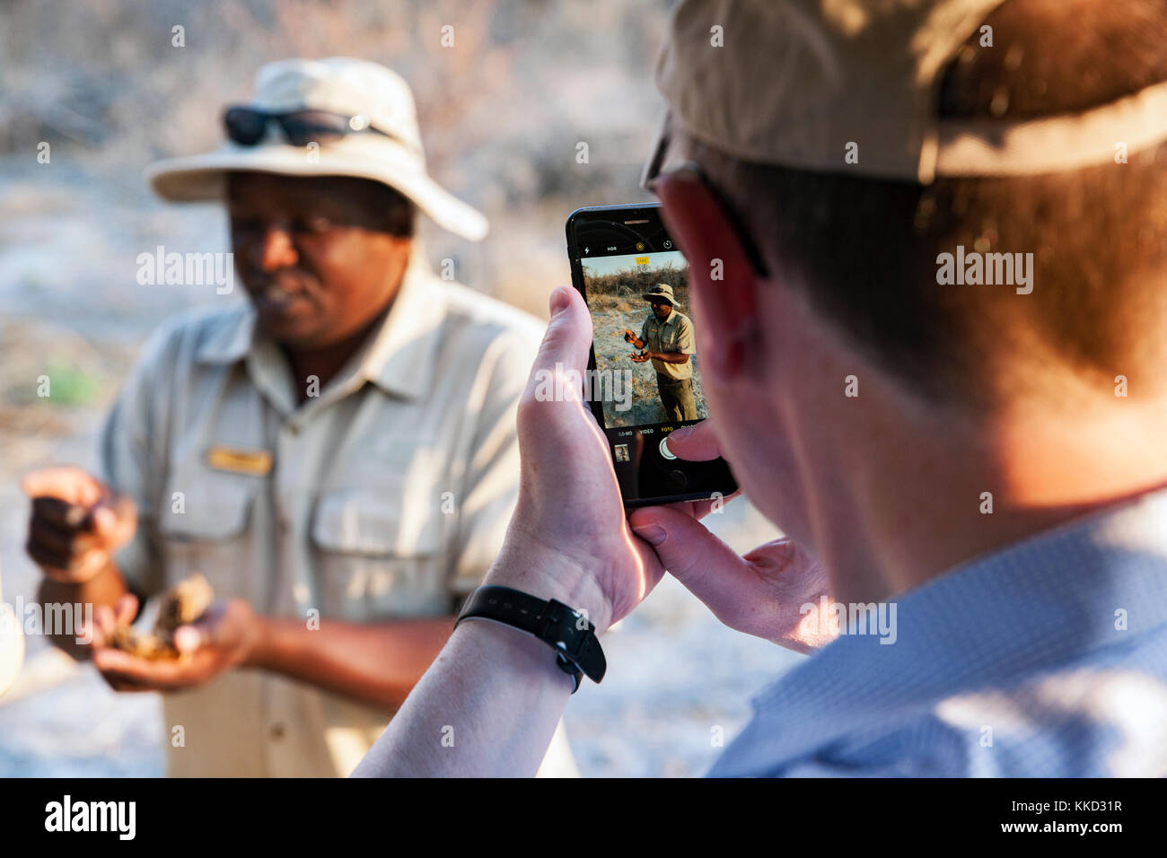 Man taking cell phone picture of guide on Sundowner Game Drive in Onguma Game Reserve, Namibia, Africa Stock Photo
