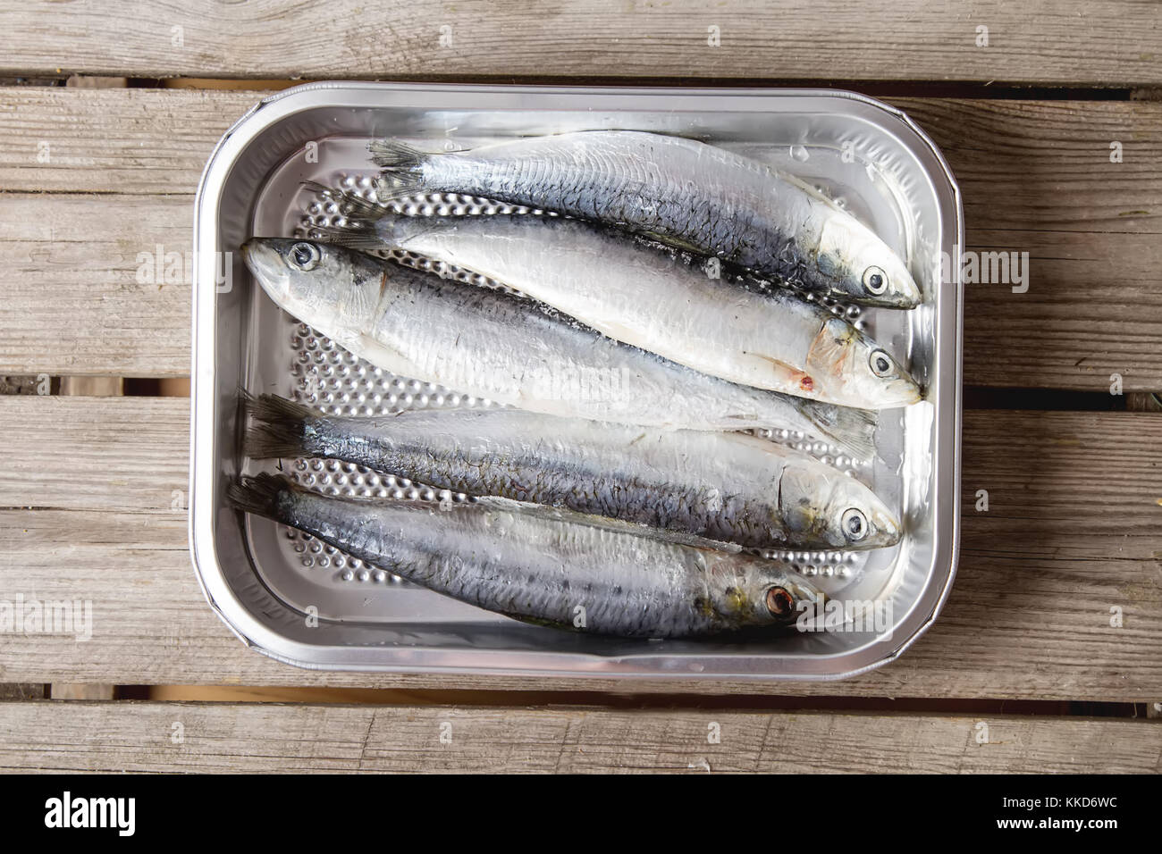 Frozen sardines. Cornish. For grill and BBG. Dark wooden background