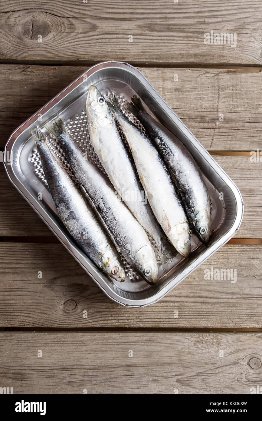 Frozen sardines. Cornish. For grill and BBG. Dark wooden background