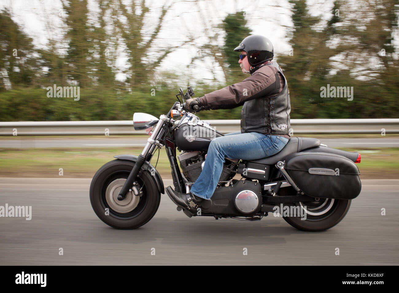 Man with a handlebar moustache riding a Harley Davidson motorcycle