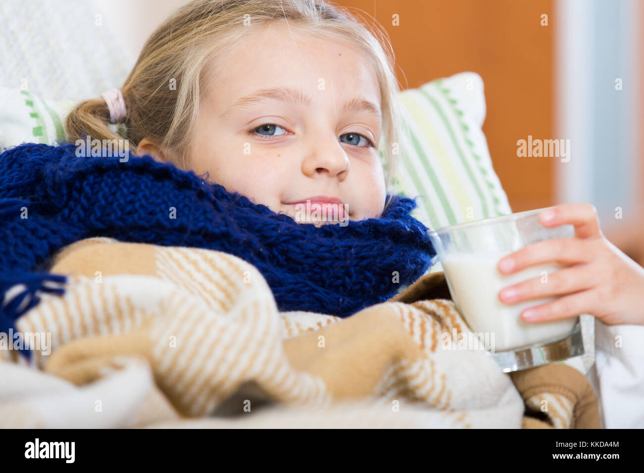 Little girl under blanket with warm milk and fever indoors Stock Photo