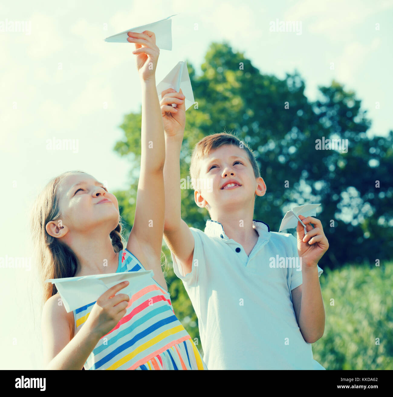 Two happy children playing with flying paper planes outdoors Stock ...