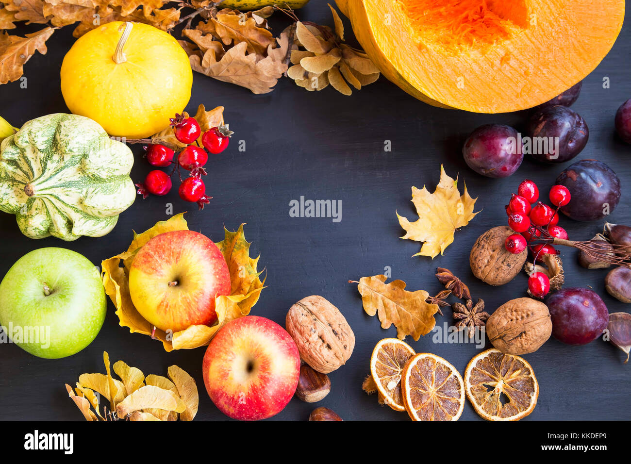 Autumn harvest frame with apples, pumpkins, nuts, plums , dried leaves on wooden background Stock Photo