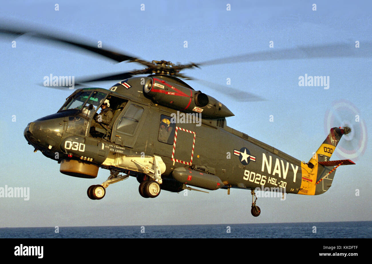 A left front view of a Helicopter Light Anti-submarine Squadron 30 (HSL-30) SH-2F Sea Sprite helicopter preparing to land on the helicopter pad of the destroyer USS NICHOLSON (DD-982). SH-2F Seasprite landing on the USS Nicholson (cropped) Stock Photo