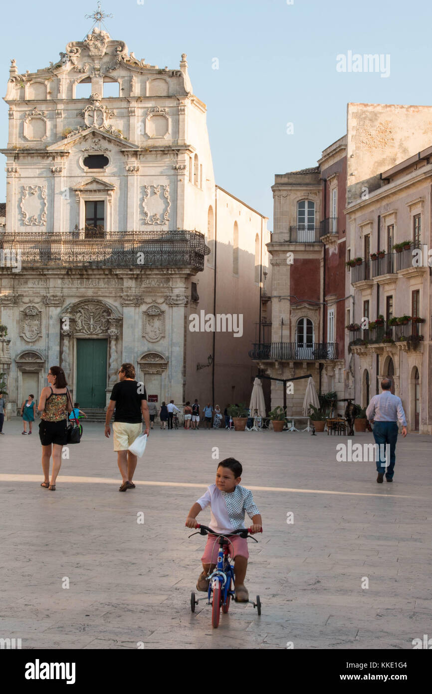 Small kid riding a bike in front of Santa Lucia alla Badia church, Sicily. Stock Photo