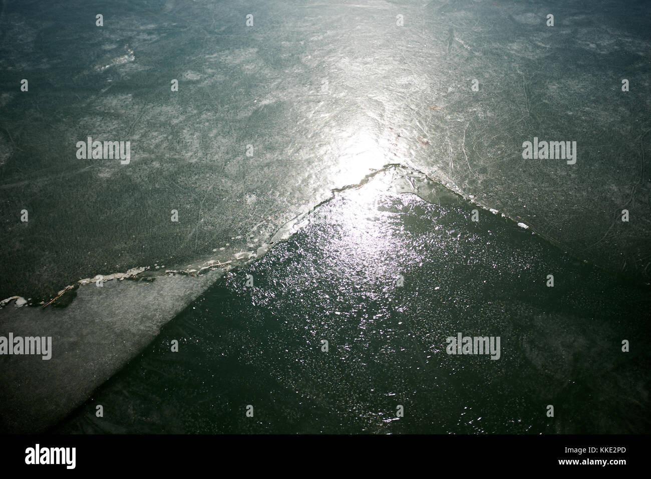 Light shining on the surface of frozen water in a pond or lake showing ...
