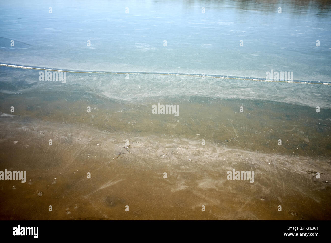 Frozen water with ice on the surface in a rural river or pond in winter ...