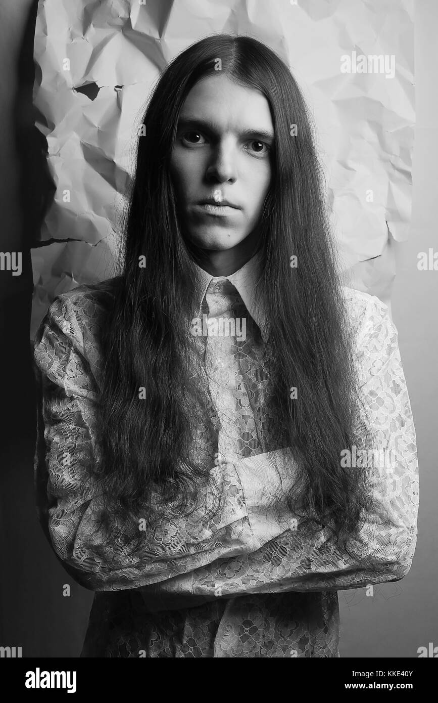 old fashioned portrait of a long-haired boy over background of wrinkled white paper. black and white studio shot Stock Photo
