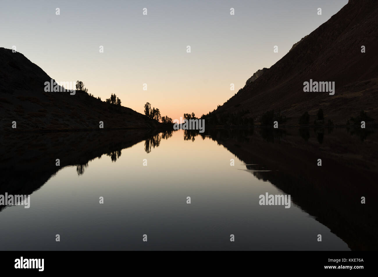 reflection of hills and trees in a mountain lake after sunset Stock Photo