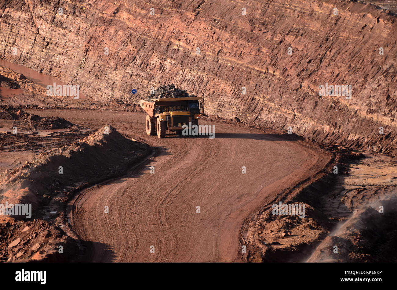 Loaded tip-truck going up along the open mine wall Stock Photo