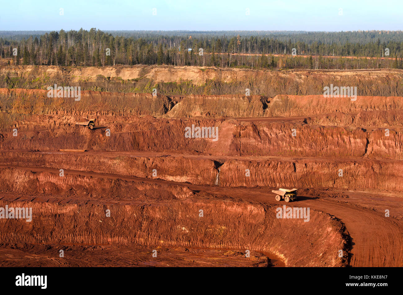 Open mine with massive trucks loaded with ore Stock Photo