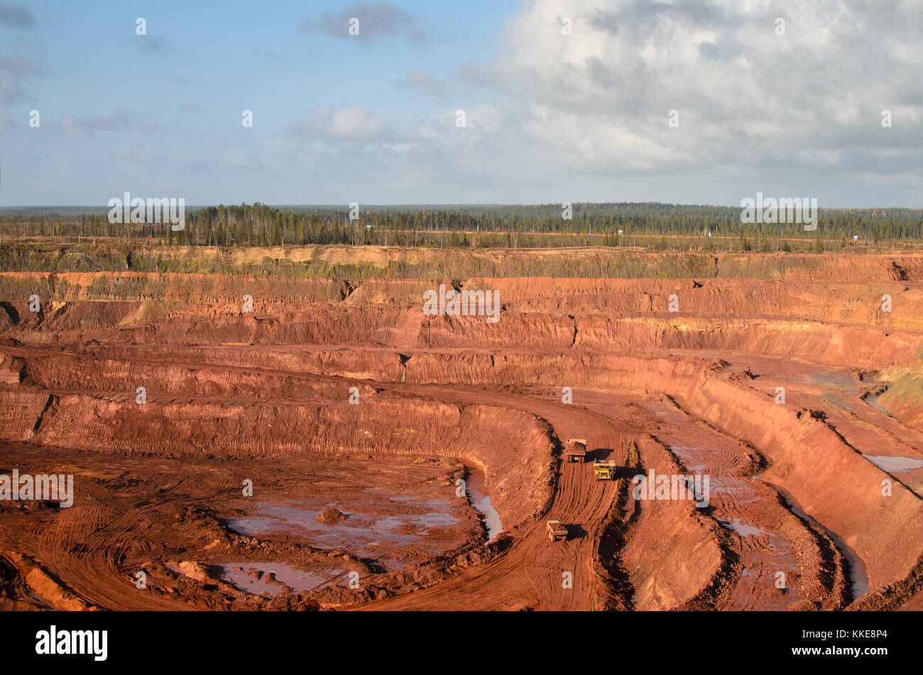 Open mine with massive trucks loaded with ore Stock Photo
