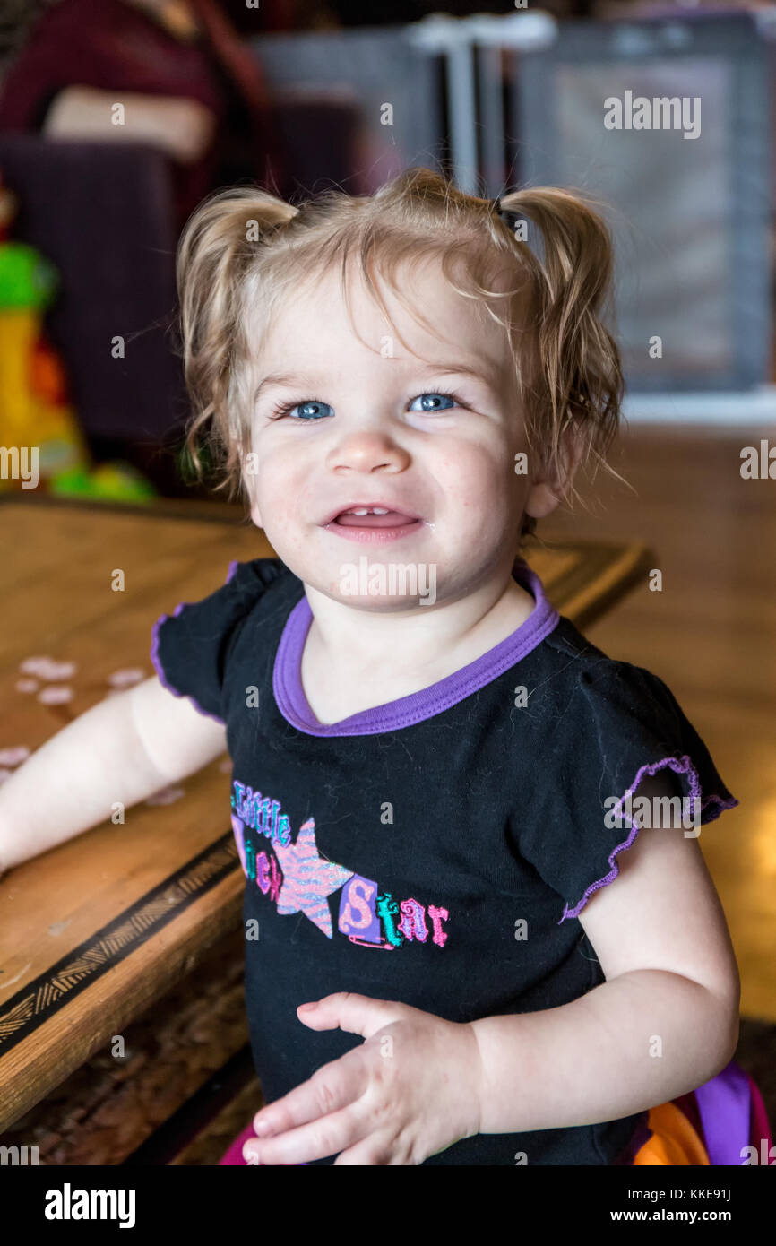 Proud one year old girl showing she can stand by her coffetable Stock