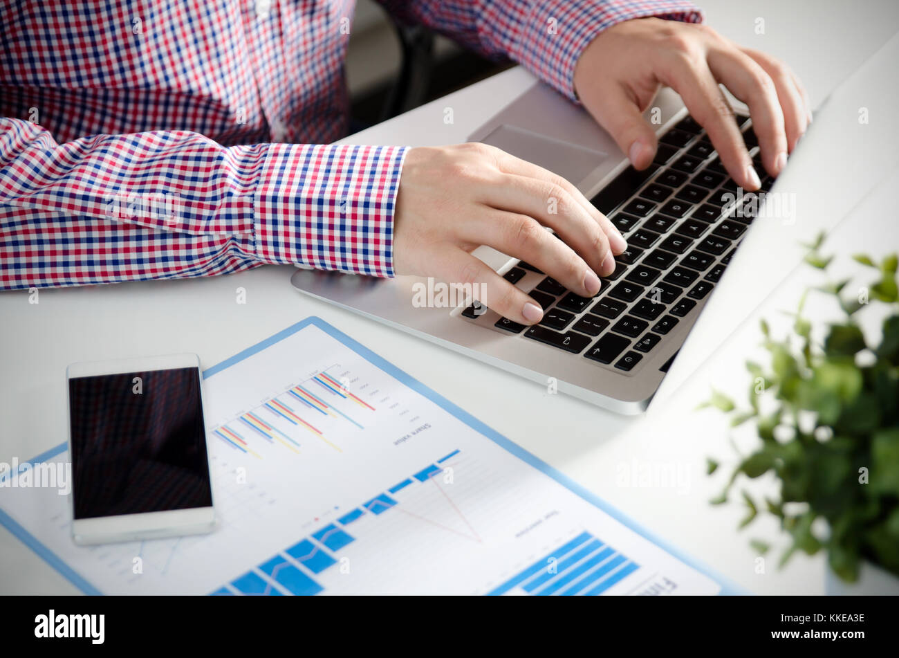 Man using mobile phone while working on laptop. Working with financial ...