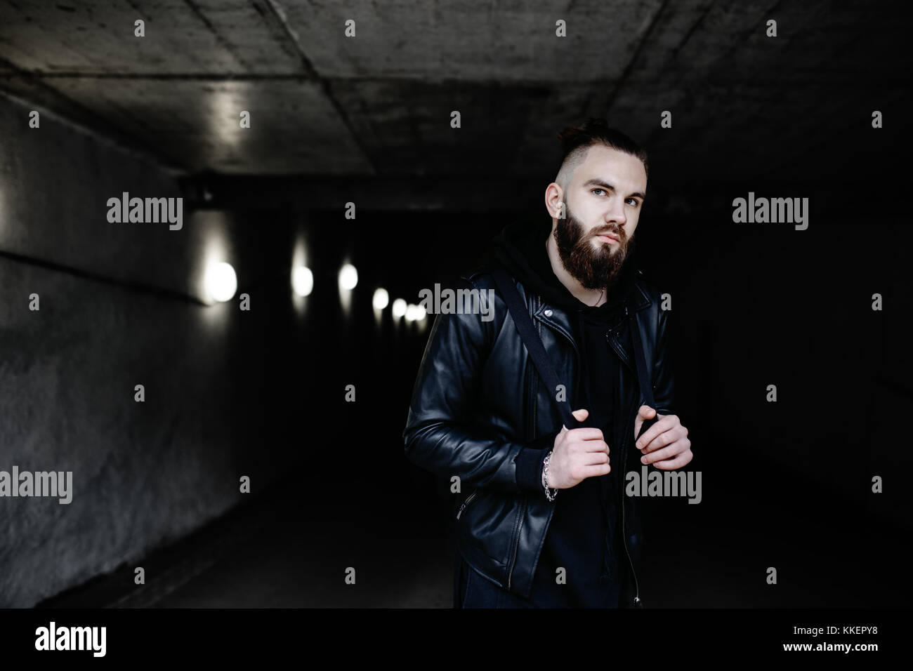 Modern young bearded man in black style clothes standing in around urban background. Stock Photo